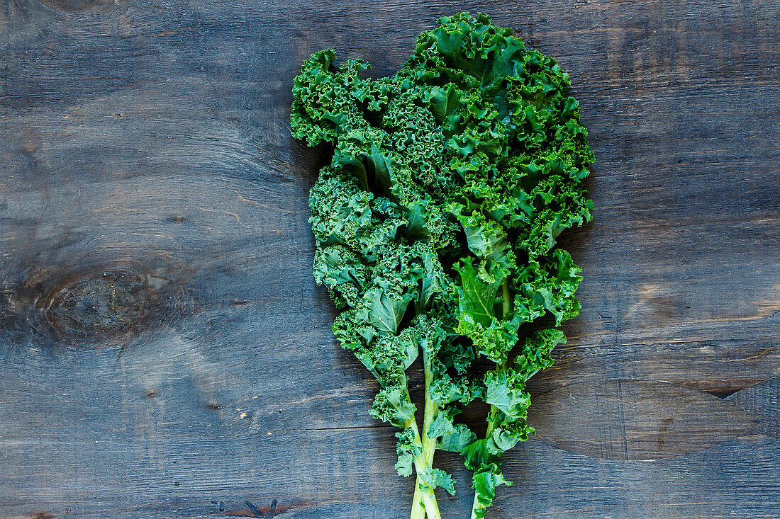 Raw green curly kale on rustic wooden background