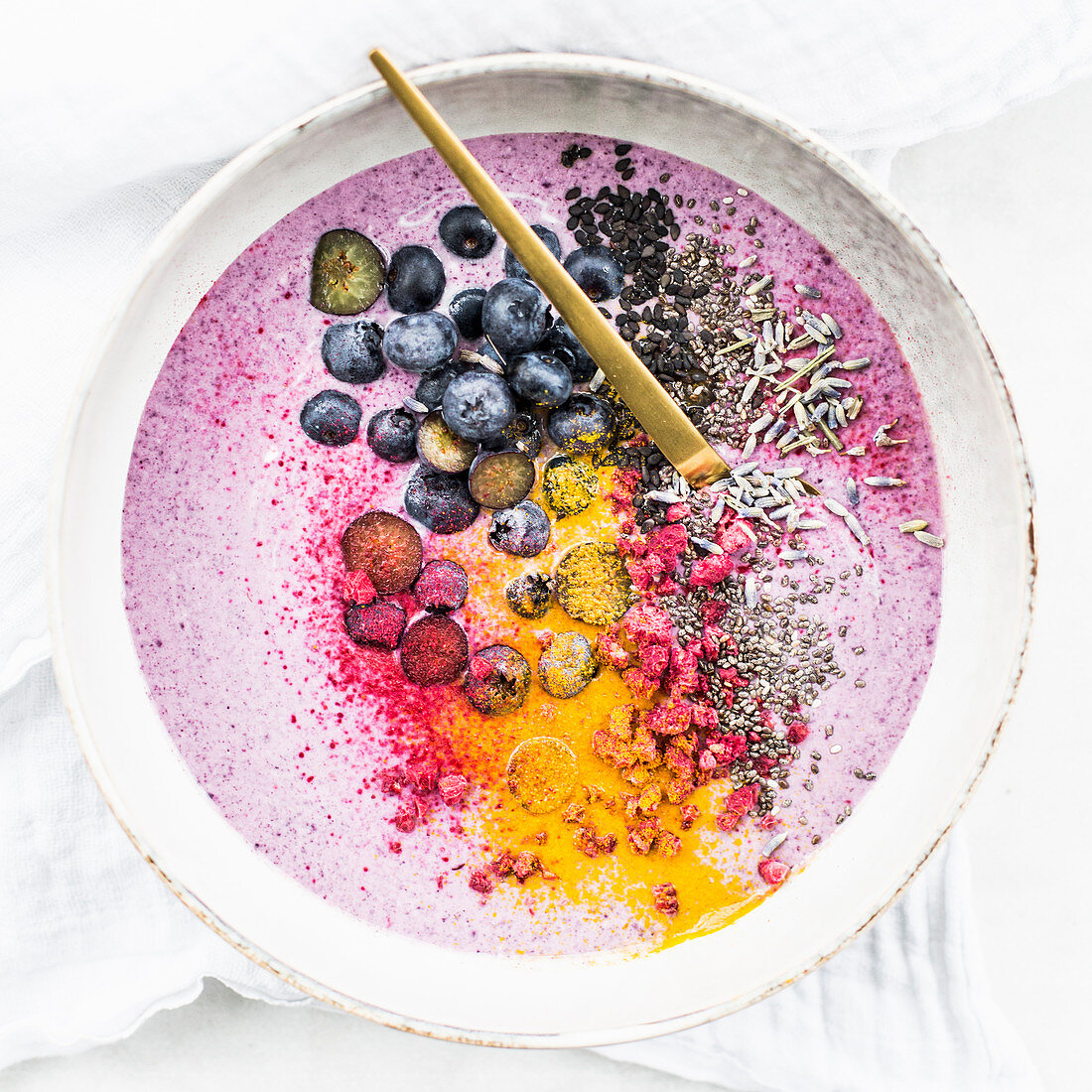 Smoothie Bowl mit Beeren, Kurkuma, Chiasamen, schwarzem Sesam und Lavendel