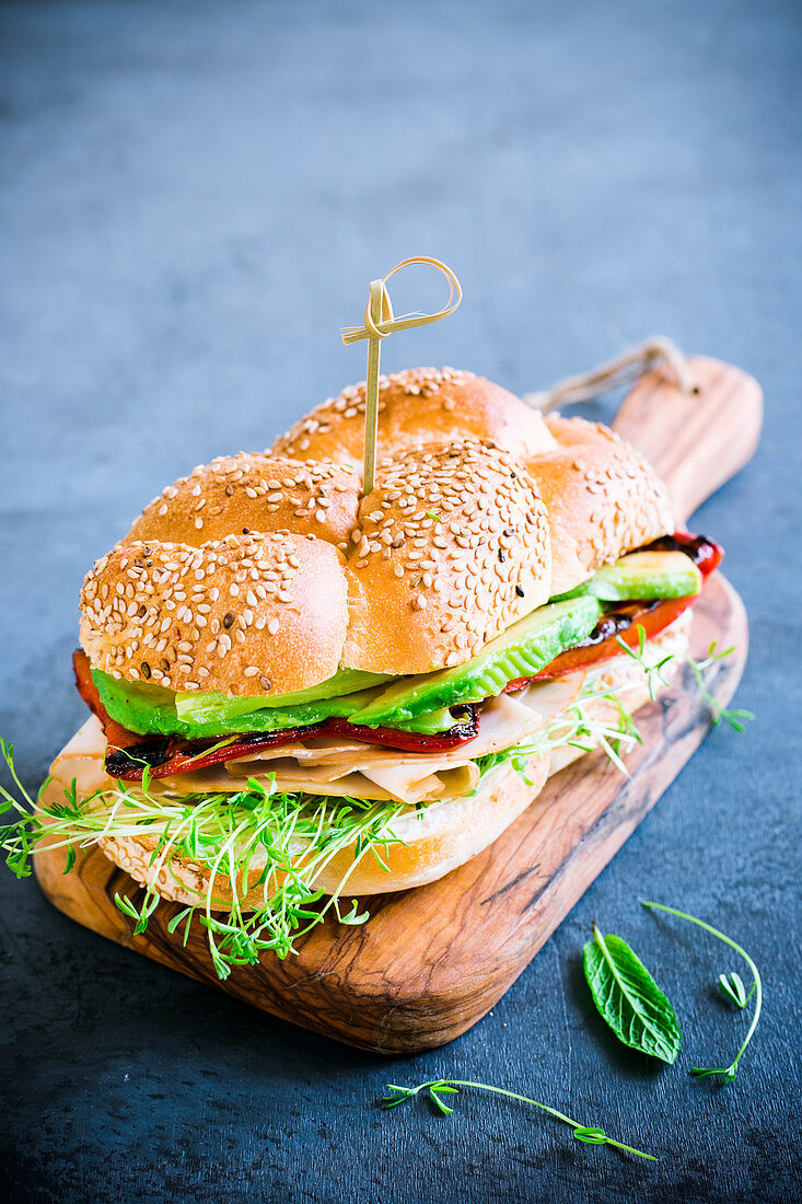 A turkey sandwich with cress, avocado and grilled peppers