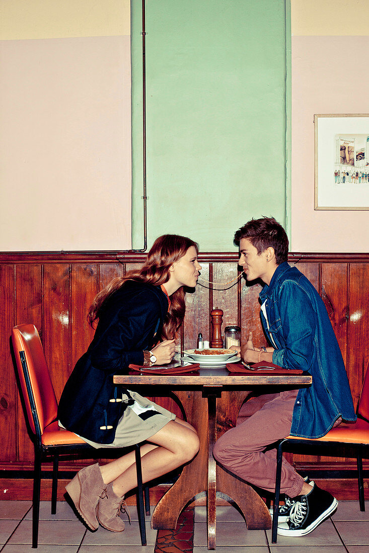 A young couple eating spaghetti in a restaurant