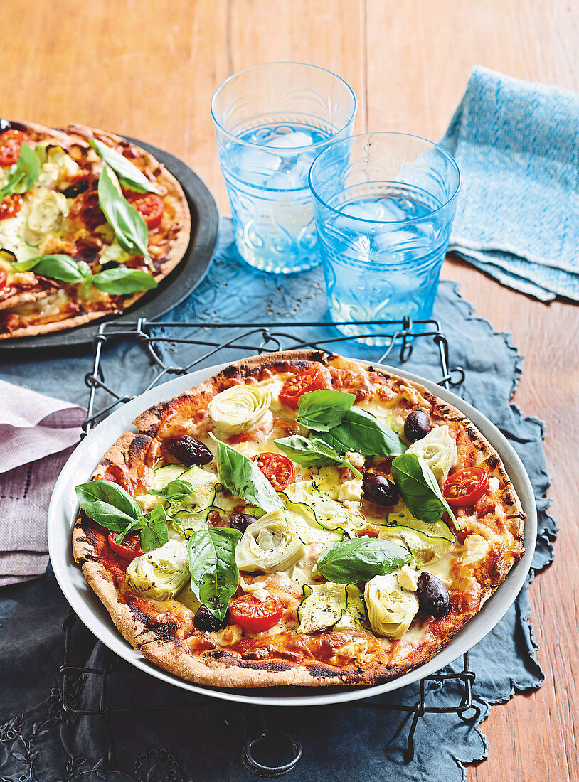 Pizza mit Artischocken, Oliven, Tomaten und Basilikum