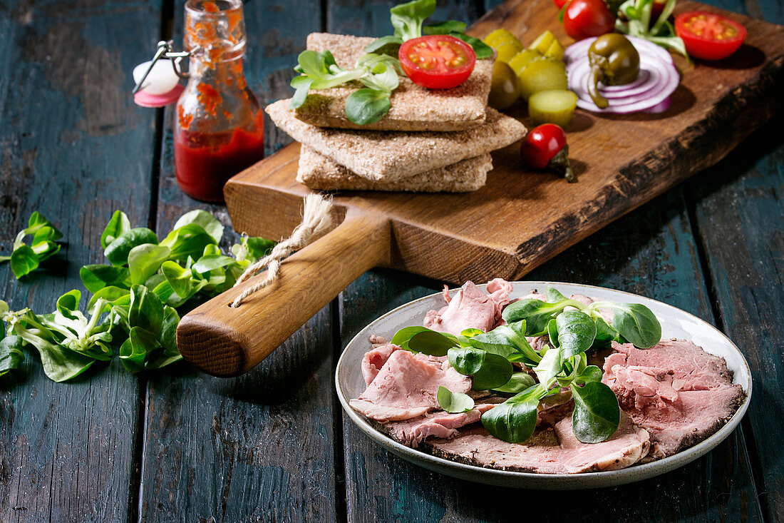 Ingredients for sandwiches: Sliced beef meat, rye whole graine bread, green salad, tomatoes, pickled cucumber, onion