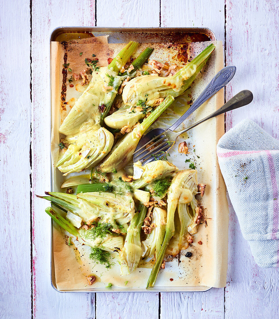 Baked fennel with cheese and nuts on a baking tray