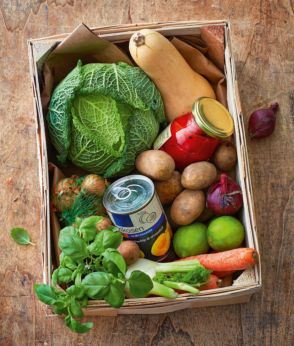 A vegetable box with canned fruit and preserved peppers