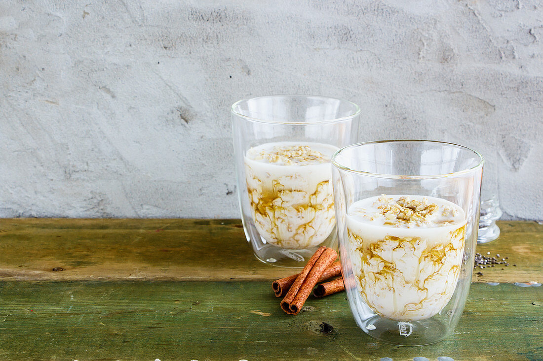 Zwei Gläser Birchermüsli mit Zimt und Honig auf altem Holztisch