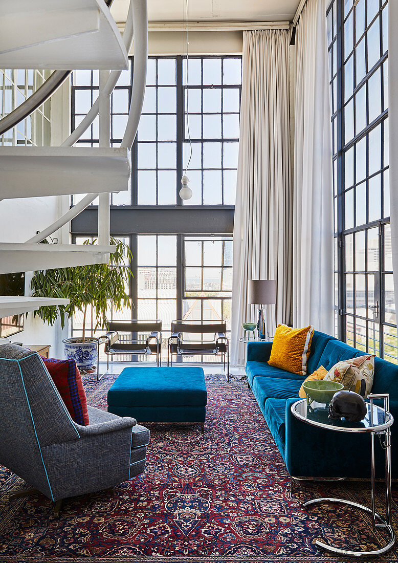 Blue and grey upholstered seating in double-height, open-plan interior with glass walls