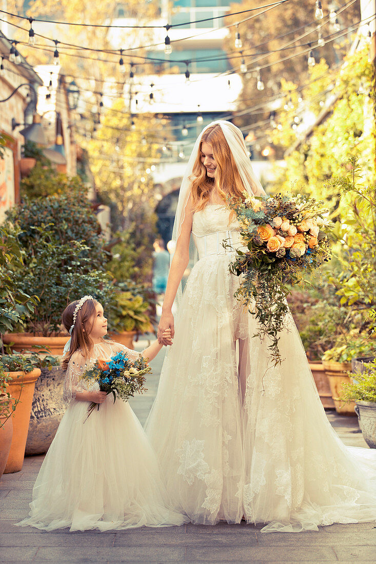 Braut in elegantem, weißem Hochzeitskleid mit Blumenmädchen