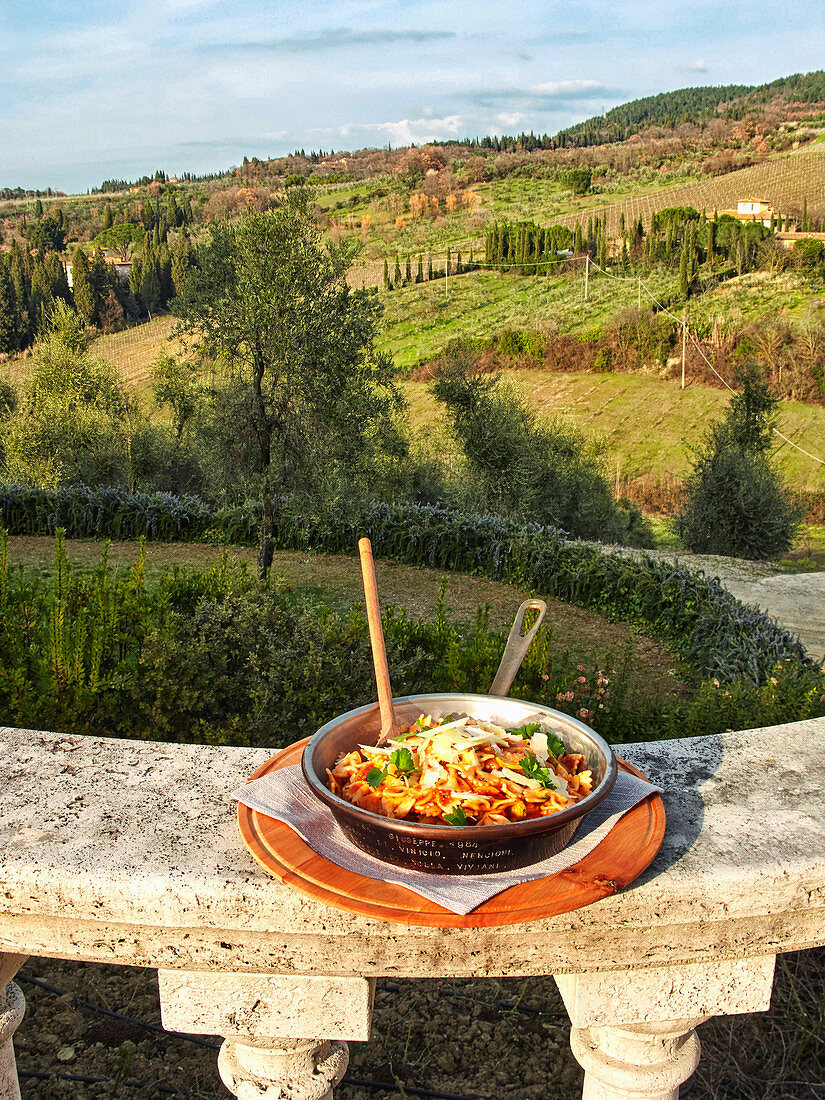 Ein Teller mit Pasta vor toskanischer Landschaft (Italien)