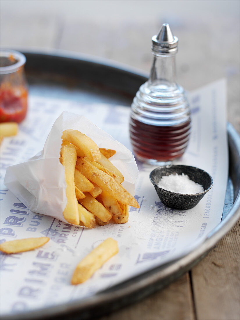 French fries in a paper bag, with a small bowl of salt