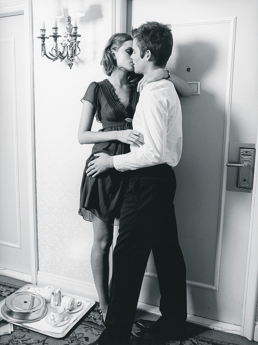 A young couple kissing outside a hotel room (black-and-white shot)