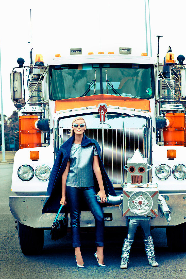 Blonde Frau und Kind als 'Roboter' verkleidet vor Lastwagen