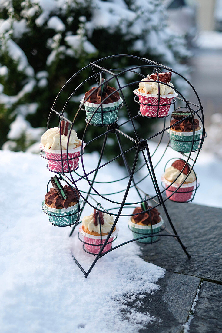 Verschiedene Cupcakes in Cupcake-Ständer im Schnee