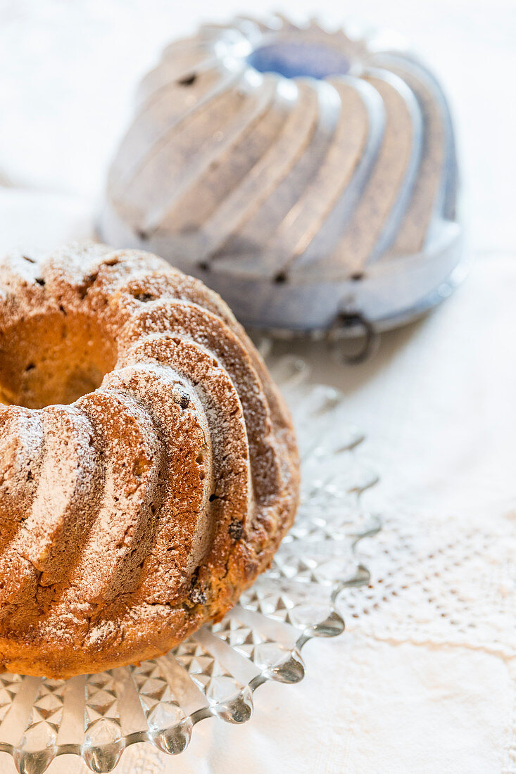 A Bundt cake and a baking tin with icing sugar