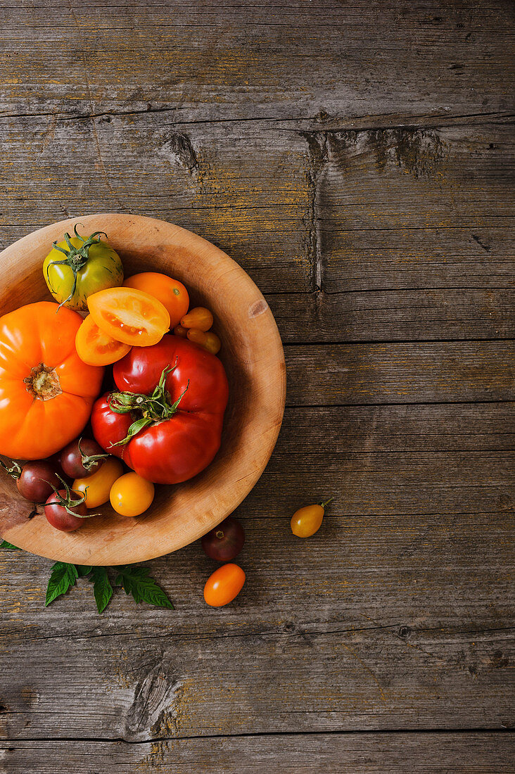 Different types of tomatoes in wooden dish