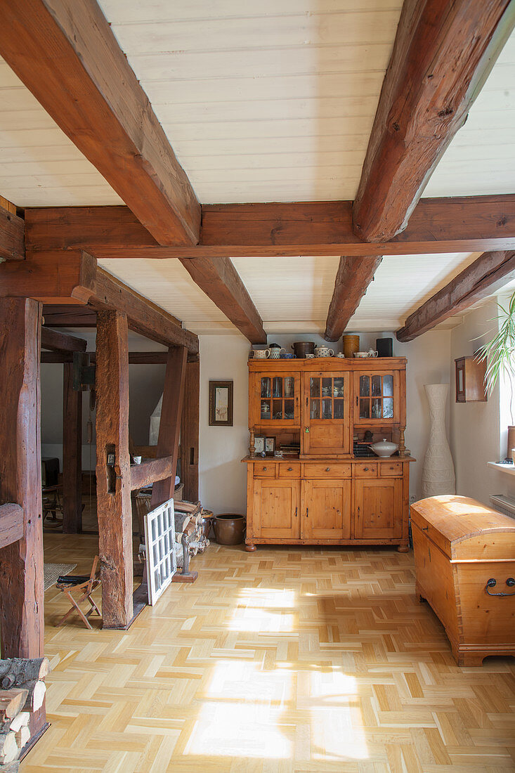 Old wooden trunk and dresser in room with wood-beamed ceiling