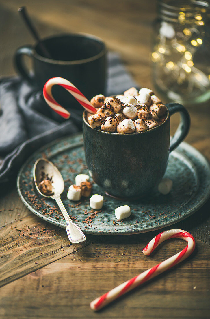Wintergetränk: Heiße Schokolade im Becher mit Marshmallows und Zuckerstange