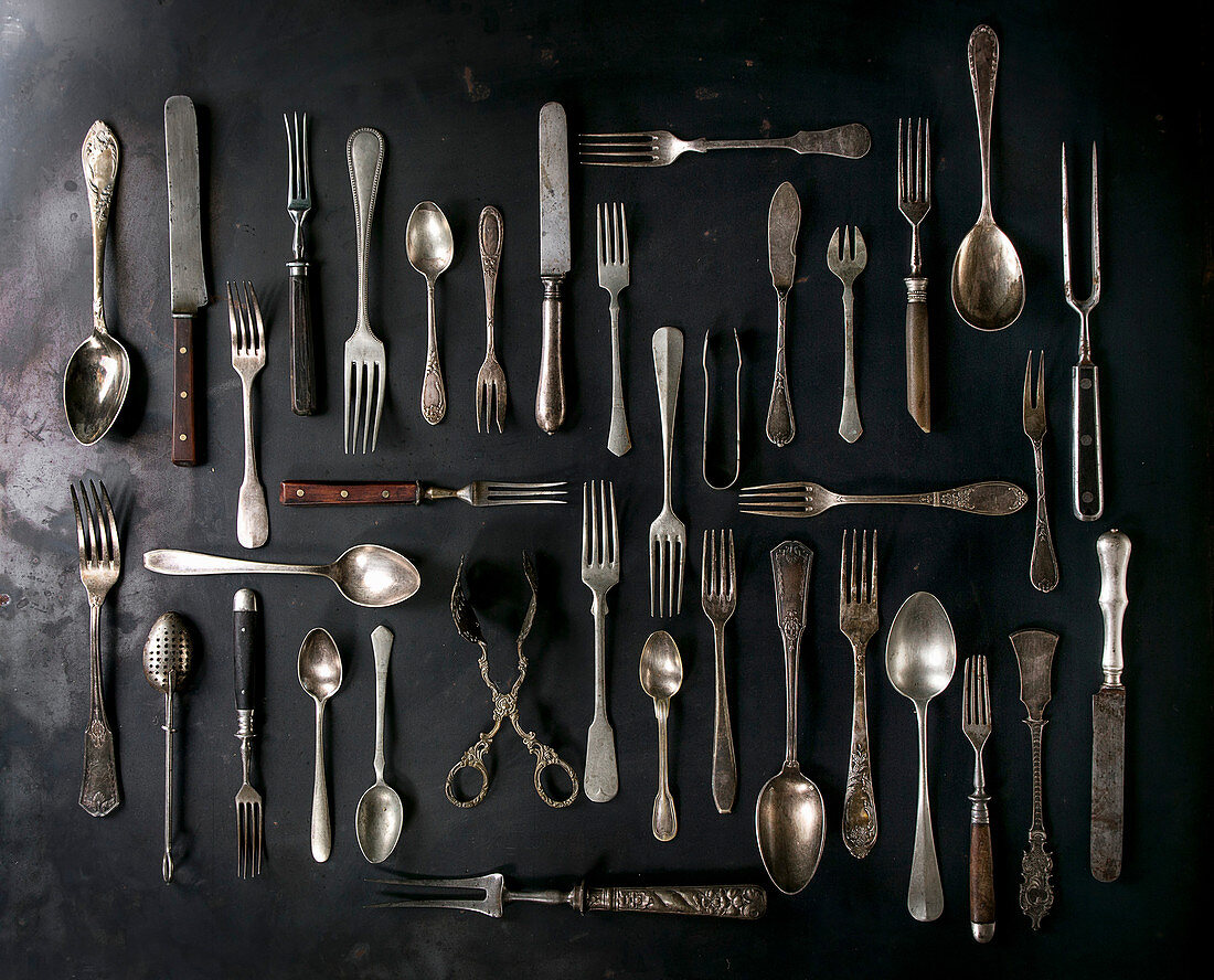 Big set of vintage cutlery over black metal background