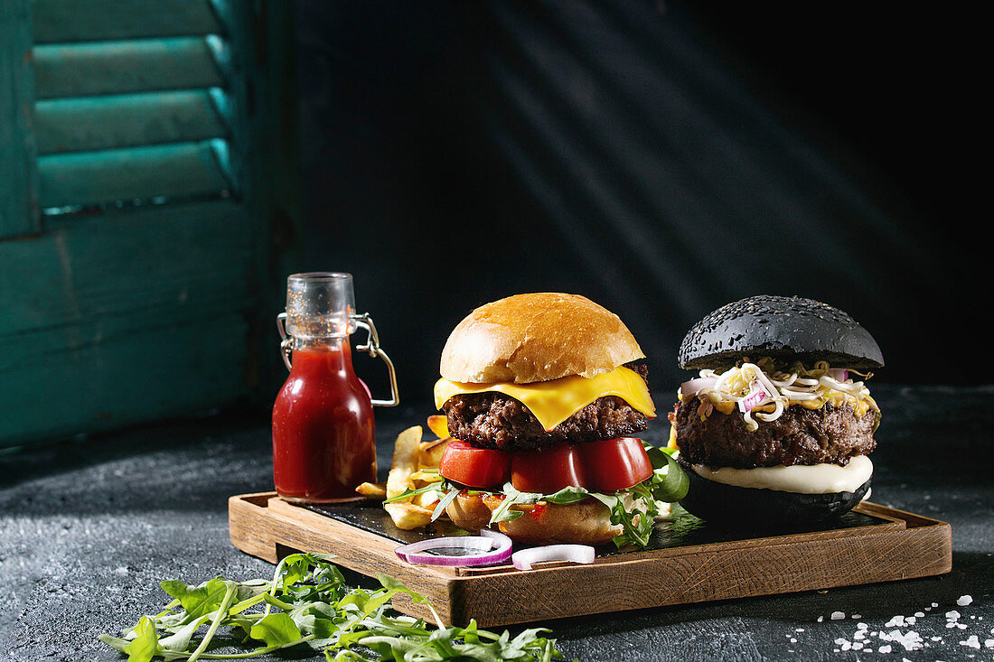 Homemade black and white buns hamburgers with beef, mozzarella cheese, sprouts, arugula