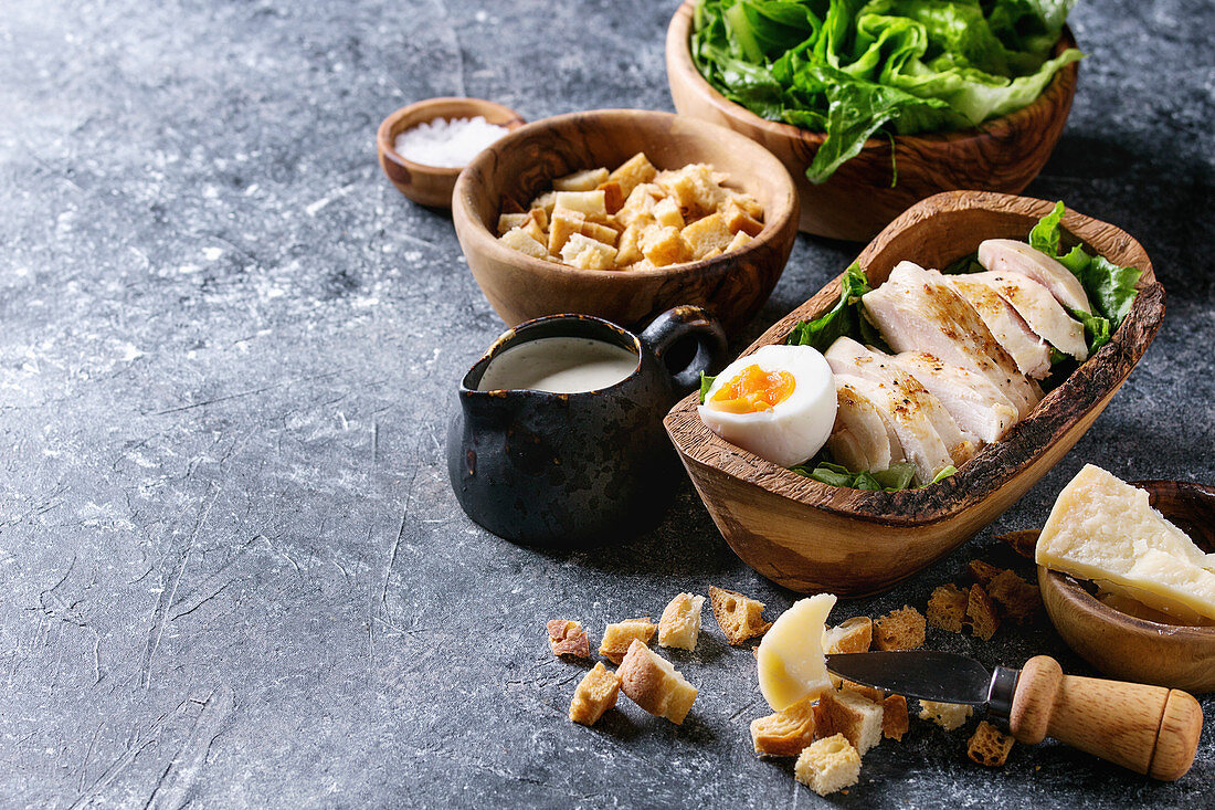 Zutaten für Caesar Salad: Hühnerbrust, Croûtons, Käse und Romanasalat