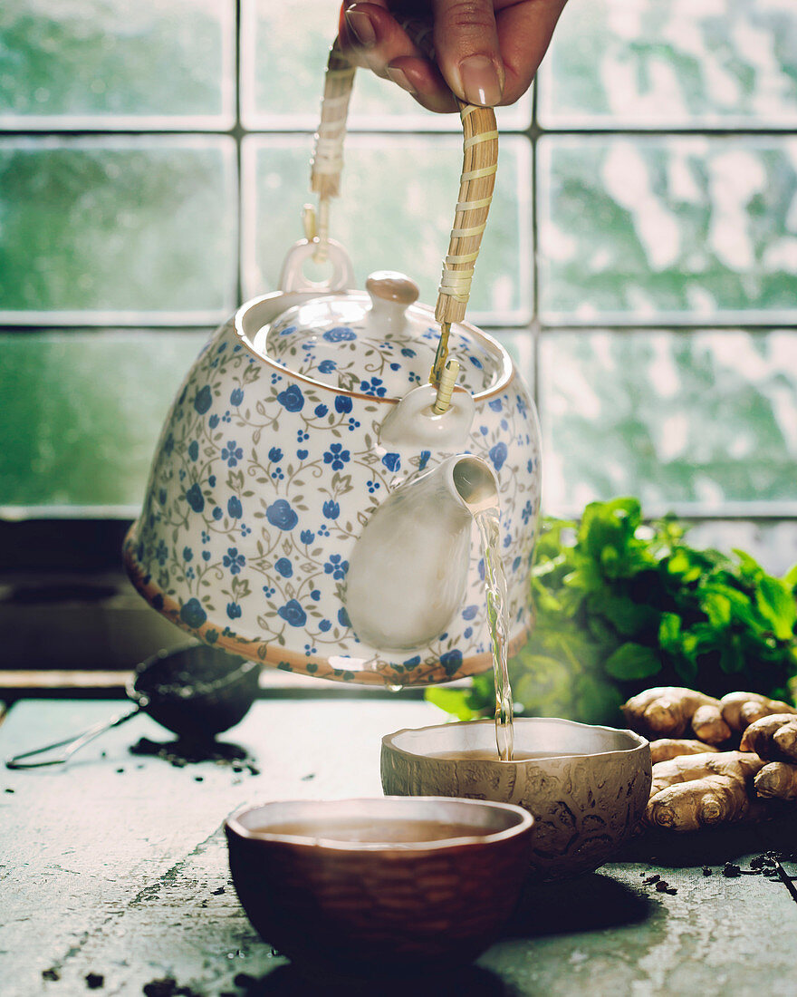 Tee wird aus nostalgischer Teekanne in Teeschalen gegossen