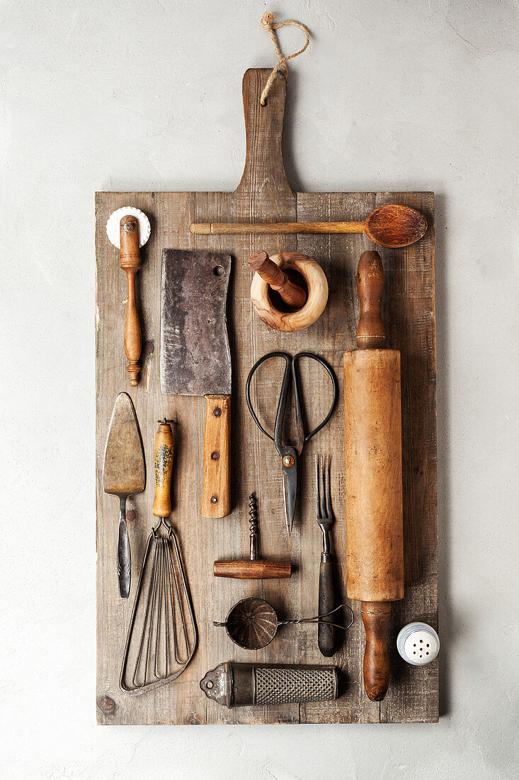 Top view of a group of vintage cooking utensils on a wood cutting board