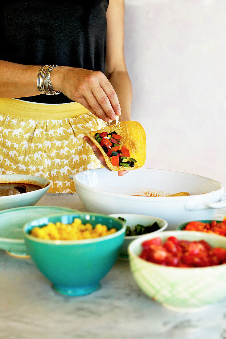 Frau füllt vegetarische Enchiladas mit verschiedenem Gemüse (Mexiko)