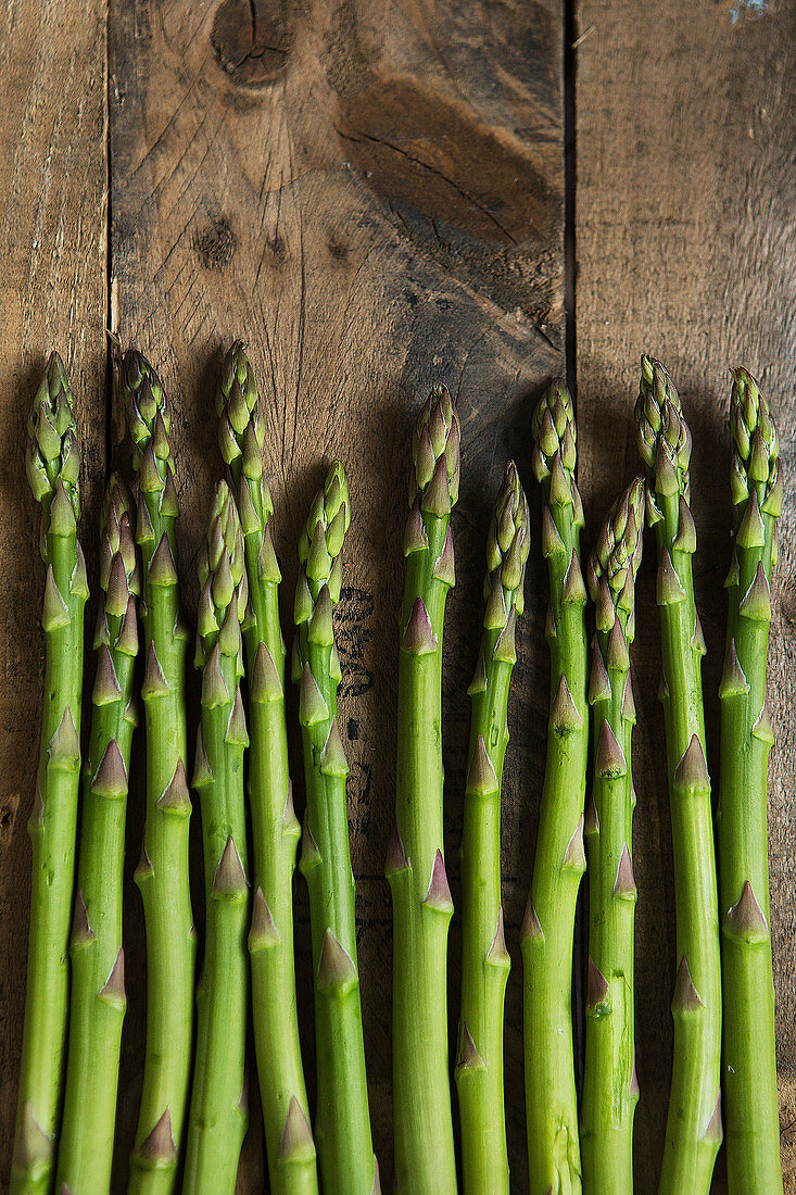 Green asparagus spears on a wooden background (top view)