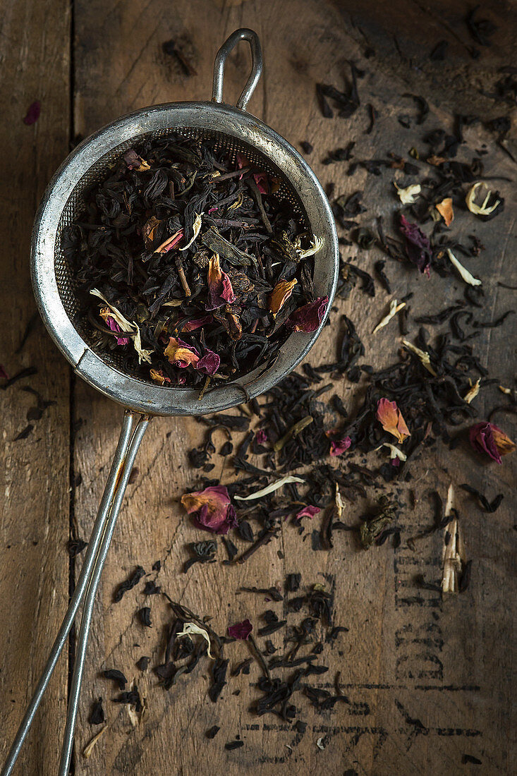 Teeblättermischung mit Rosenblüten und weissen Kornblüten in Sieb