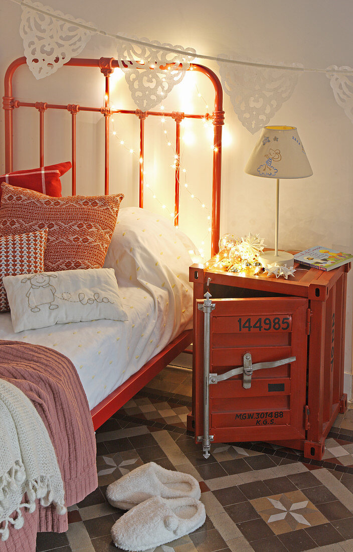 Metal crate used as bedside table next to red bed in child's bedroom