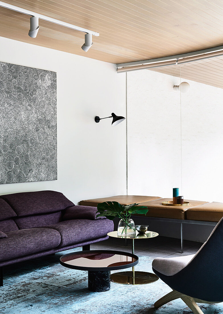 Purple sofa and leather bench in the lounge area with glass partition