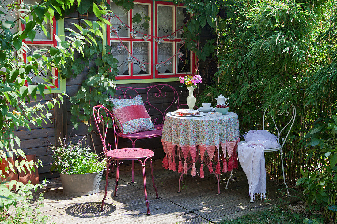 Romantic seating area on terrace outside wooden cabin in garden