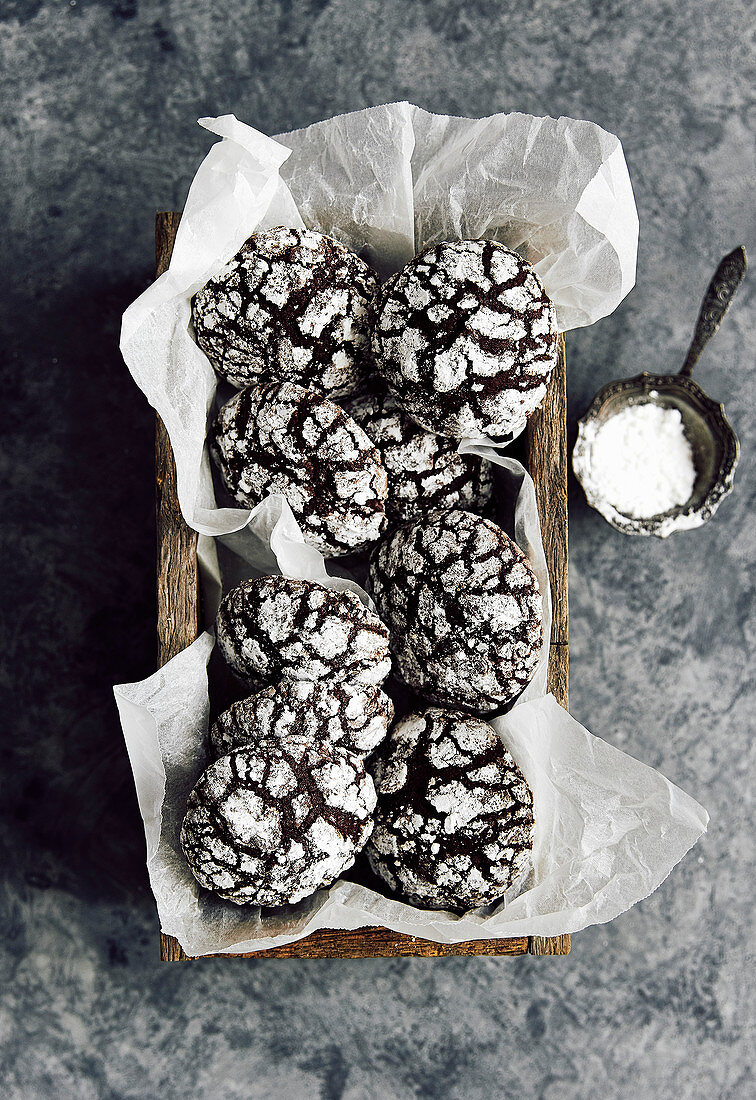 chocolate crinkle cookies in wooden box, dusted with icing sugar