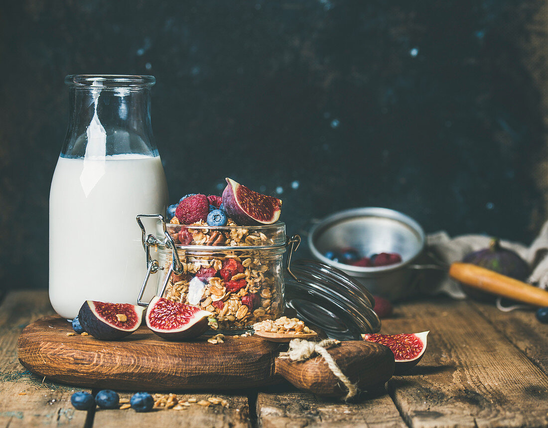 Healthy vegan breakfast, oatmeal granola with bottled almond milk, fresh fruit and berries over wooden table background, copy space