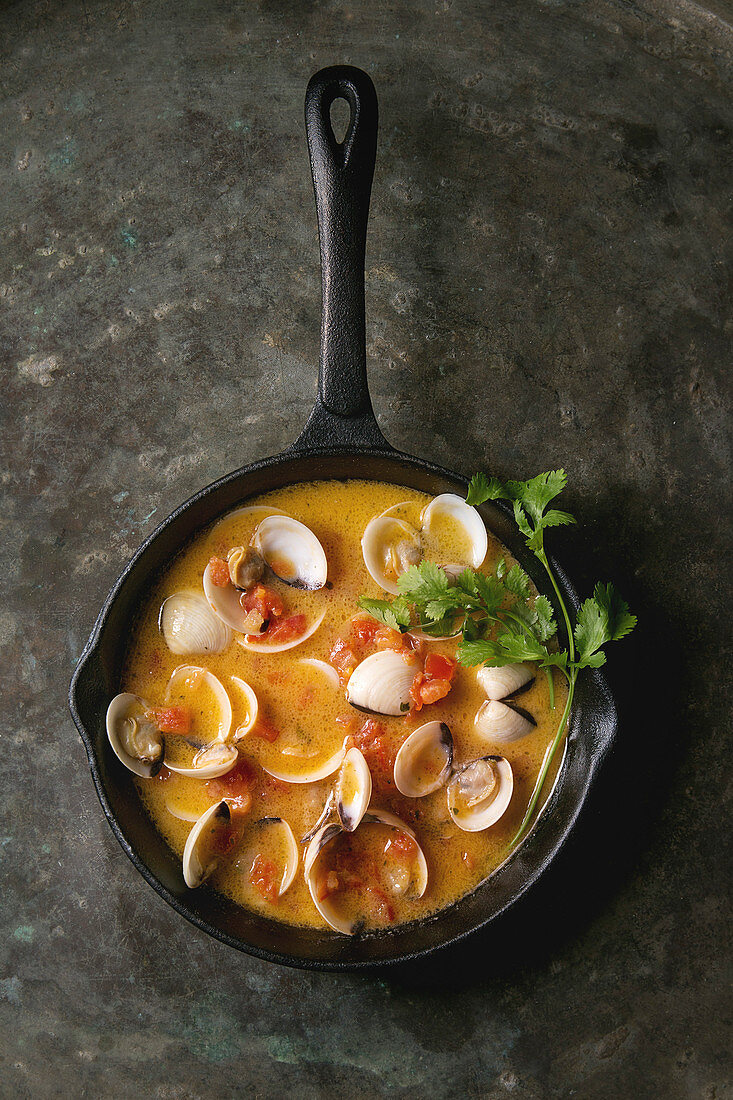 Vongole in tomato cream sauce for pasta in cast-iron pan over old metal texture background