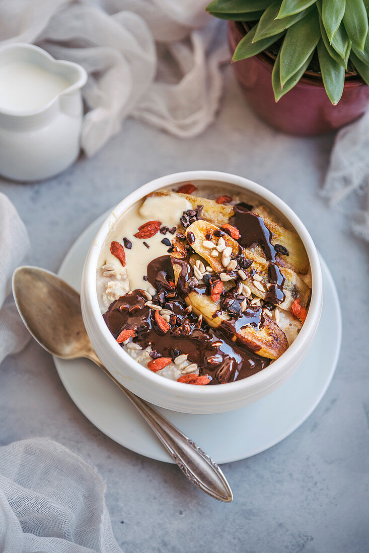 Porridge-Bowl mit karamellisierten Bananen, Schokolade, Kakaonibs und Goji