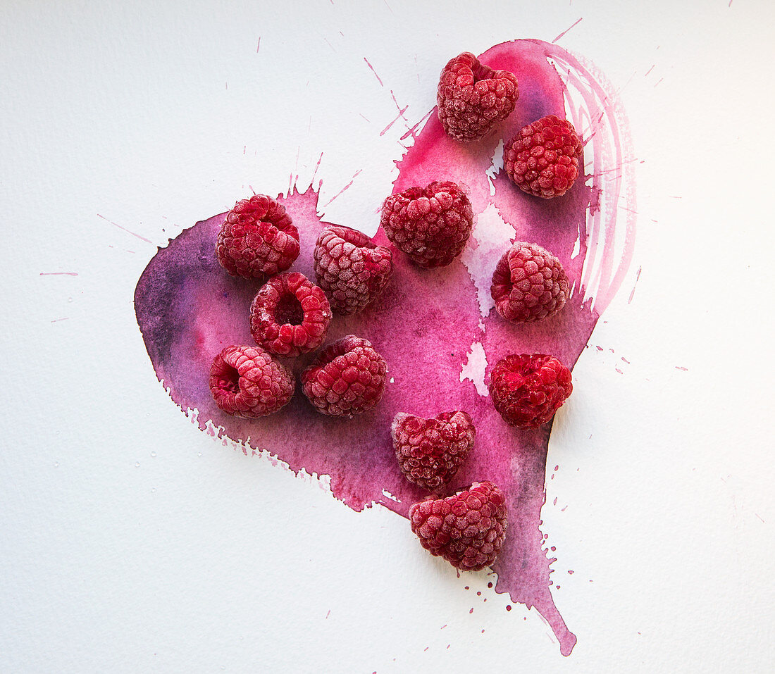 Frozen raspberries on a hand painted pink watercolour heart