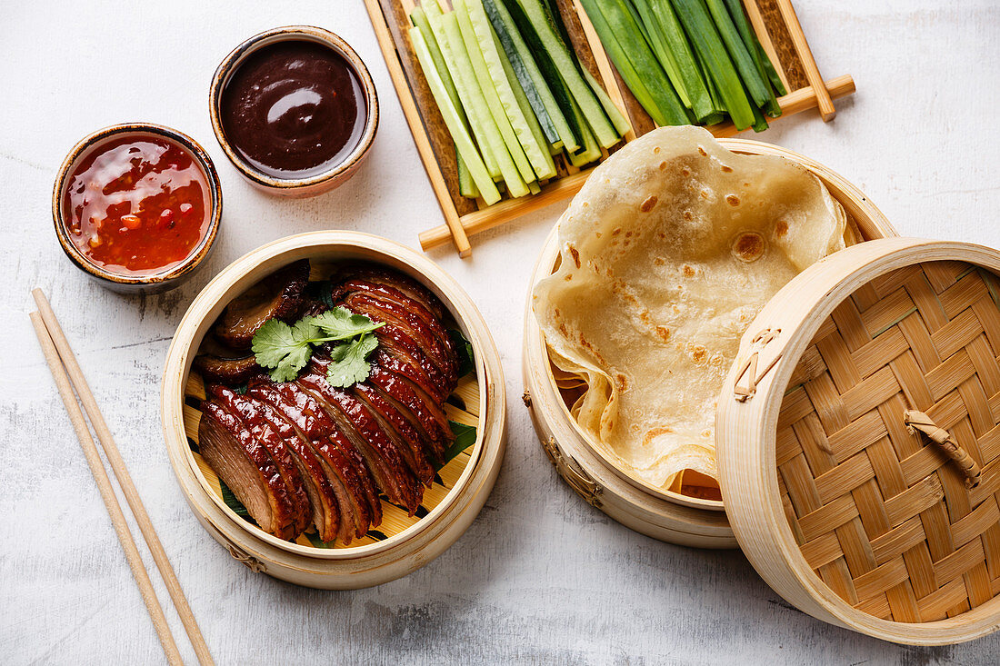 Peking-Ente und Pfannkuchen im Bambusdämpfer serviert mit Dips und Gemüse (China)