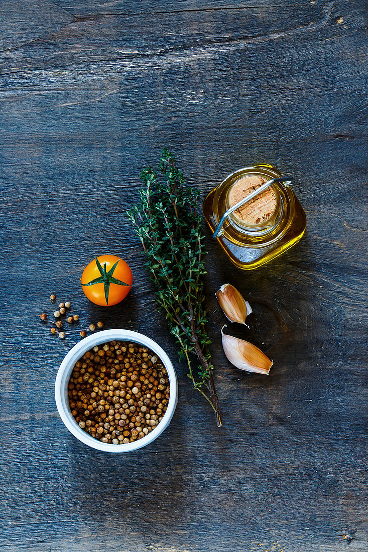 Olivenöl, Kräuter, Tomate, Knoblauch und Gewürze auf Holzuntergrund
