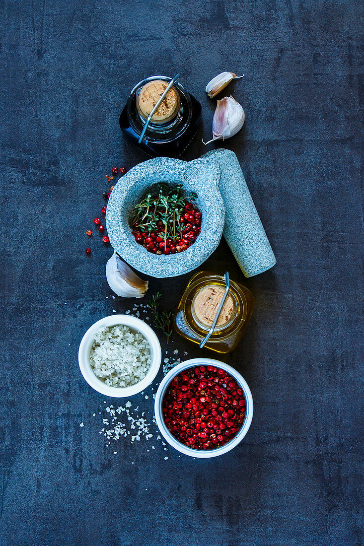 Top view of olive oil, balsamic vinegar, mortar and pestle with various colorful spices on dark grunge background