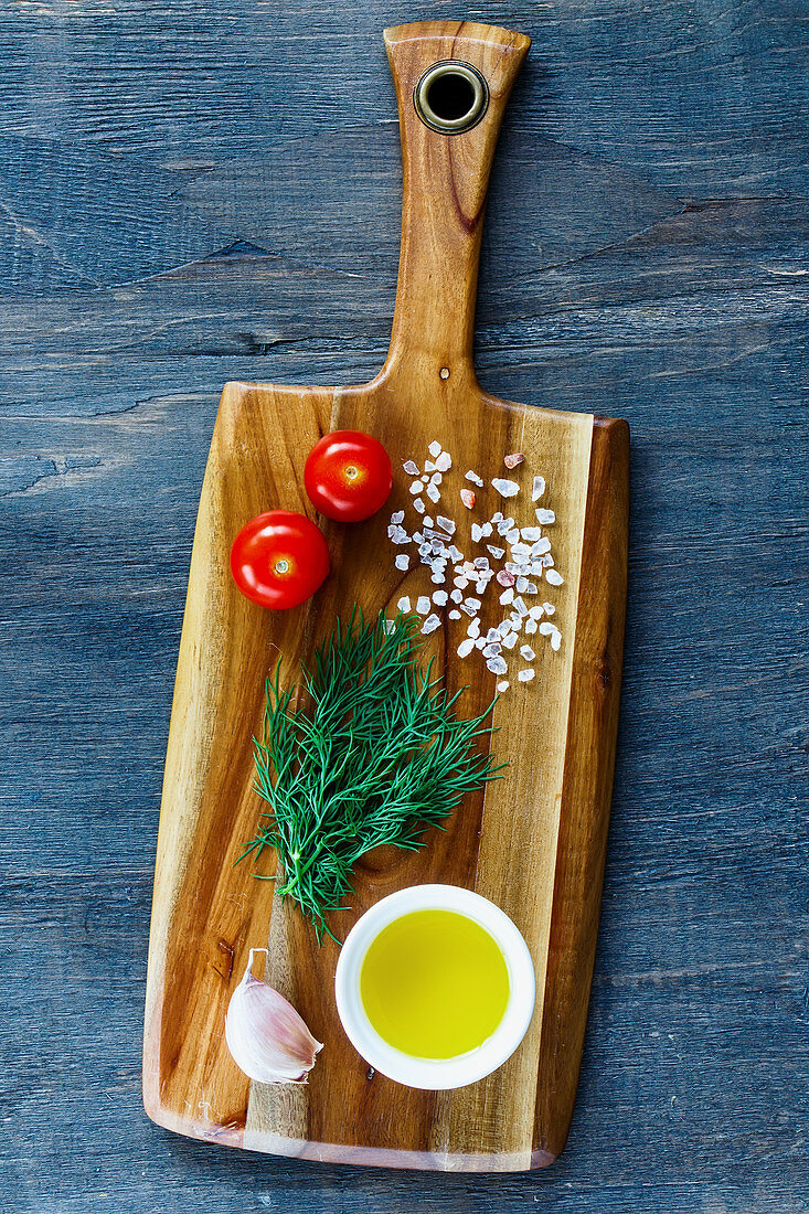 Olivenöl, Knoblauch, Kräuter, Tomate und Salz auf Holzschneidebrett