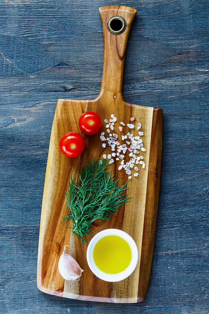 Rural wooden kitchen table with cutting board and ingredients on vintage background