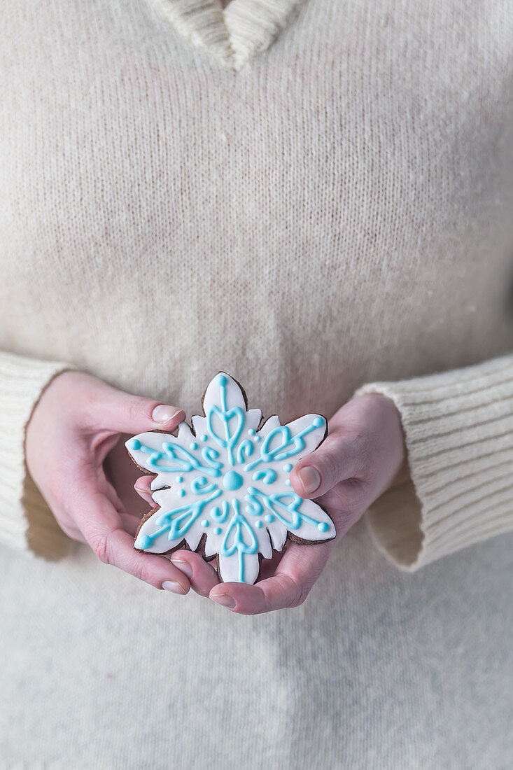 Woman holding gingerbread snowflake cookie