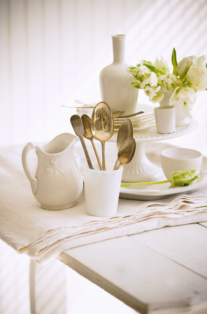 Weisses Geschirr und Silberlöffel auf Holztisch