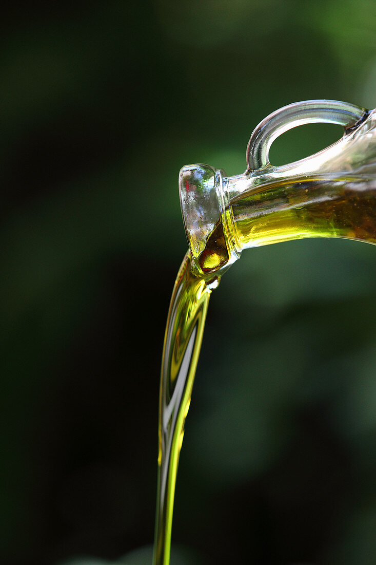 Olivenöl fliesst aus einer Karaffe
