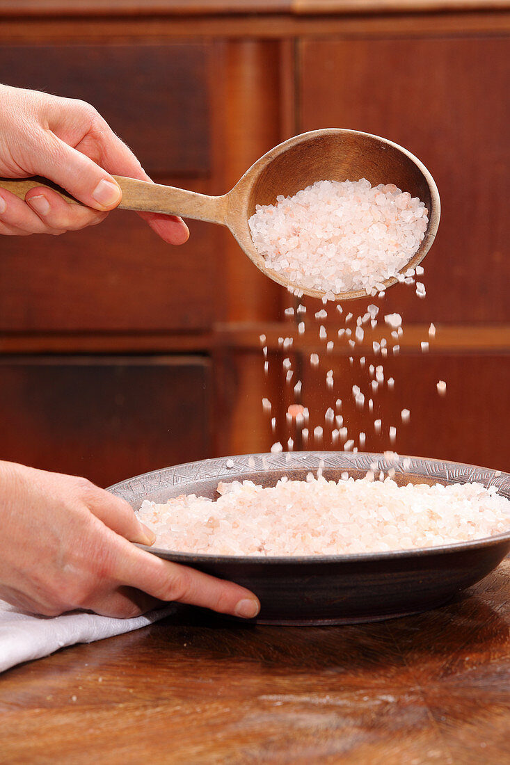 Salt being tipped from a wooden spoon