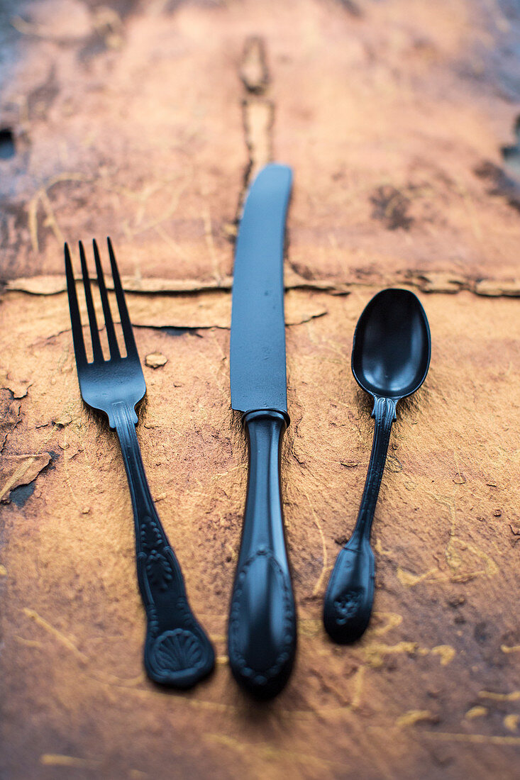 Black vintage knife fork and spoon on a copper slate