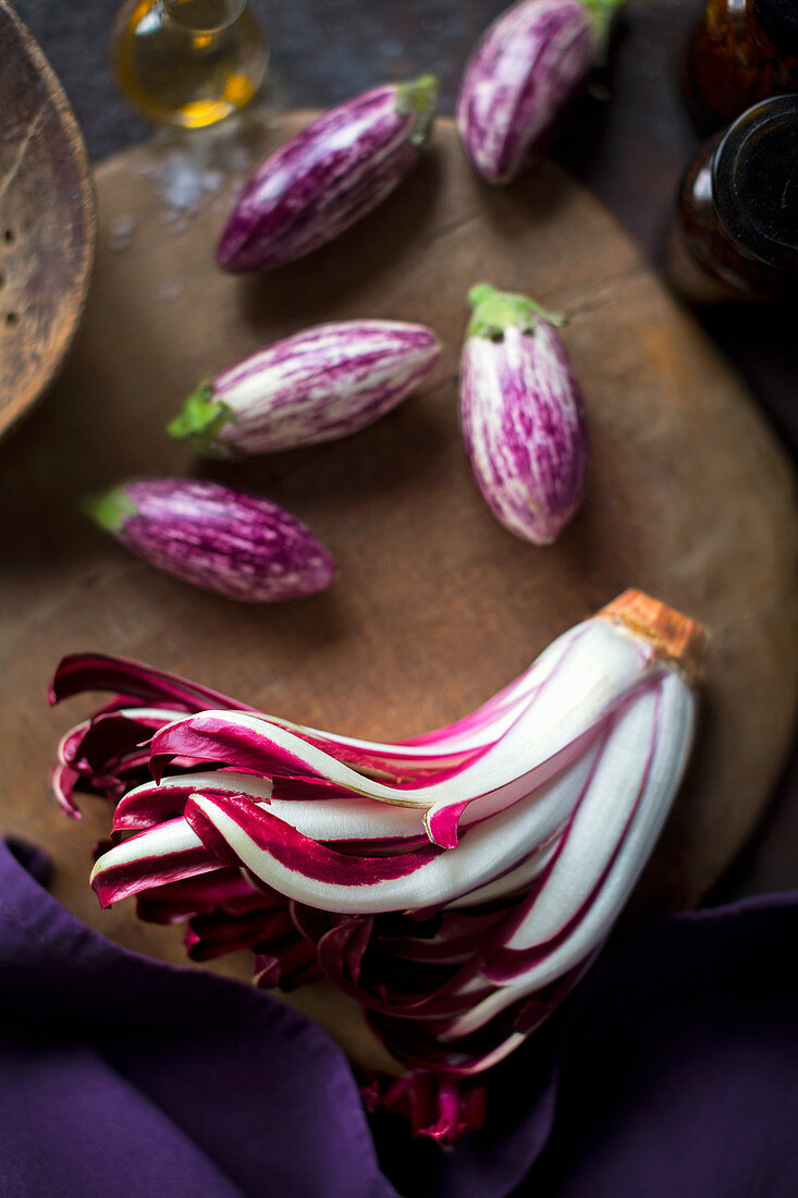 An arrangement of of trevisio and small aubergines on an old wooden board