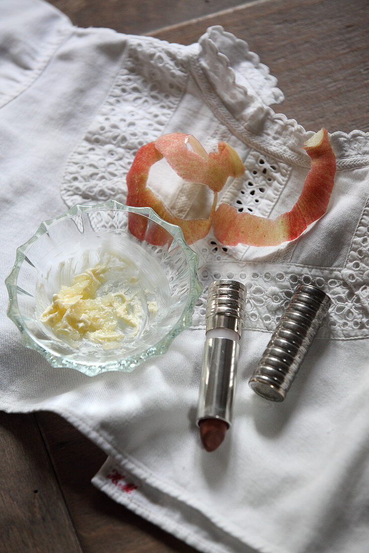 Natural lip care in a small bowl, with apple peel and lipstick