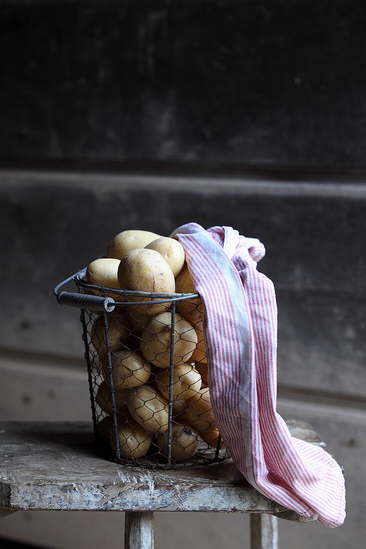 Potatoes in a wire basket with a tea towel