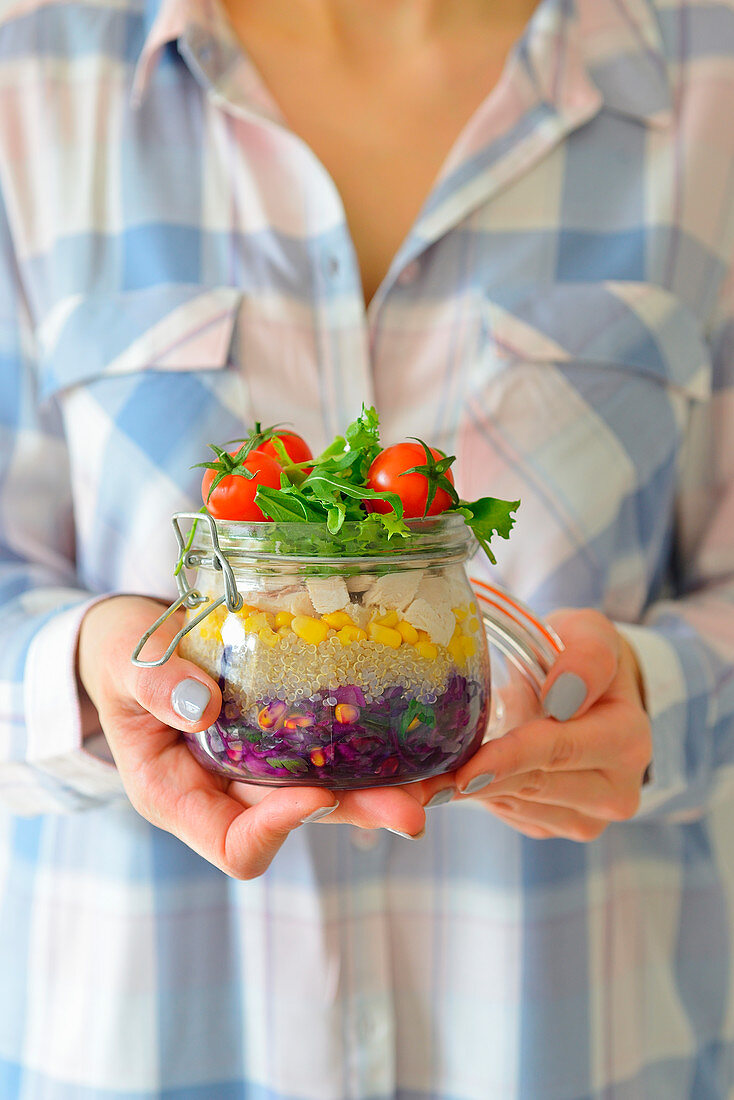 Salad for work in a jar cherry tomatoes chicken lettuce woman holding a jar with salad lunch
